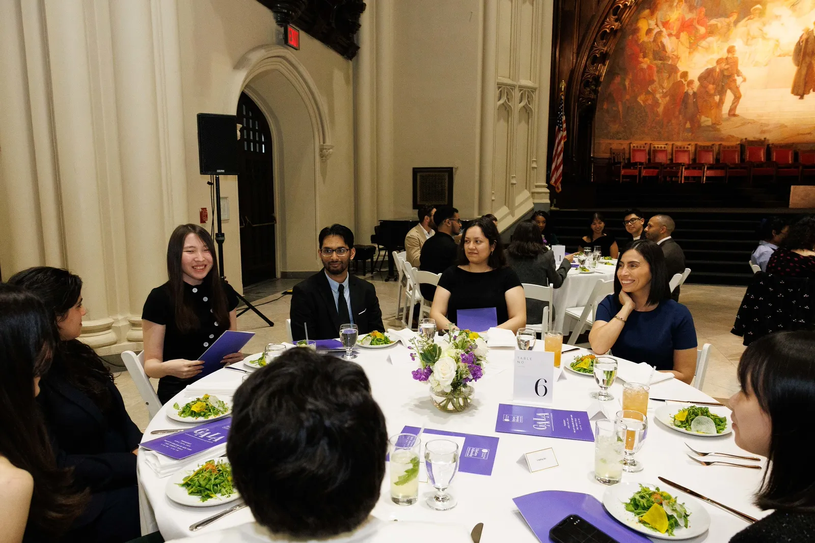 IICD staff, faculty, as well as past fellows seated around a table eating salads and holding event programs