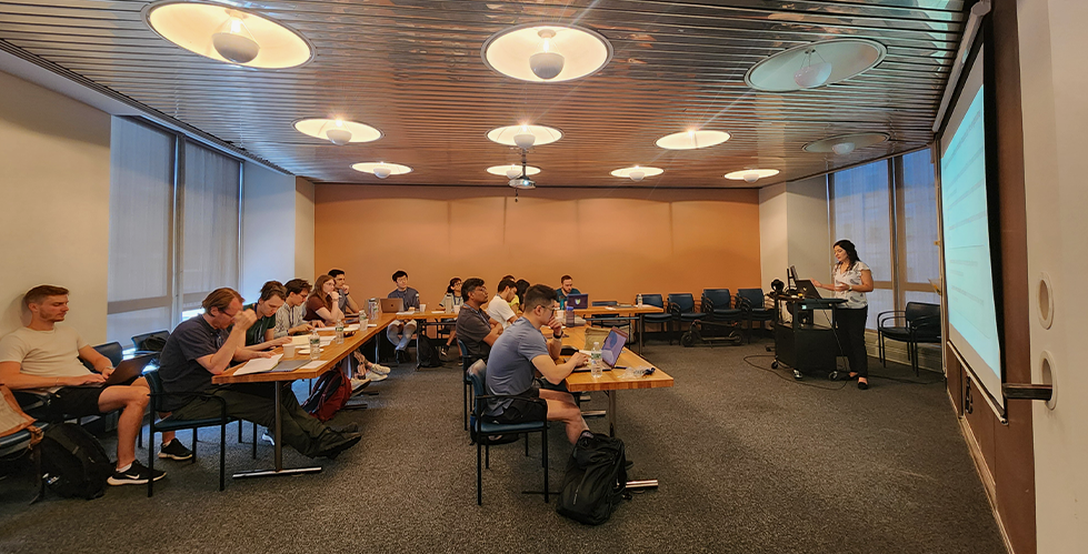 a group of people sitting at desks and listening to a presenter in a classroom