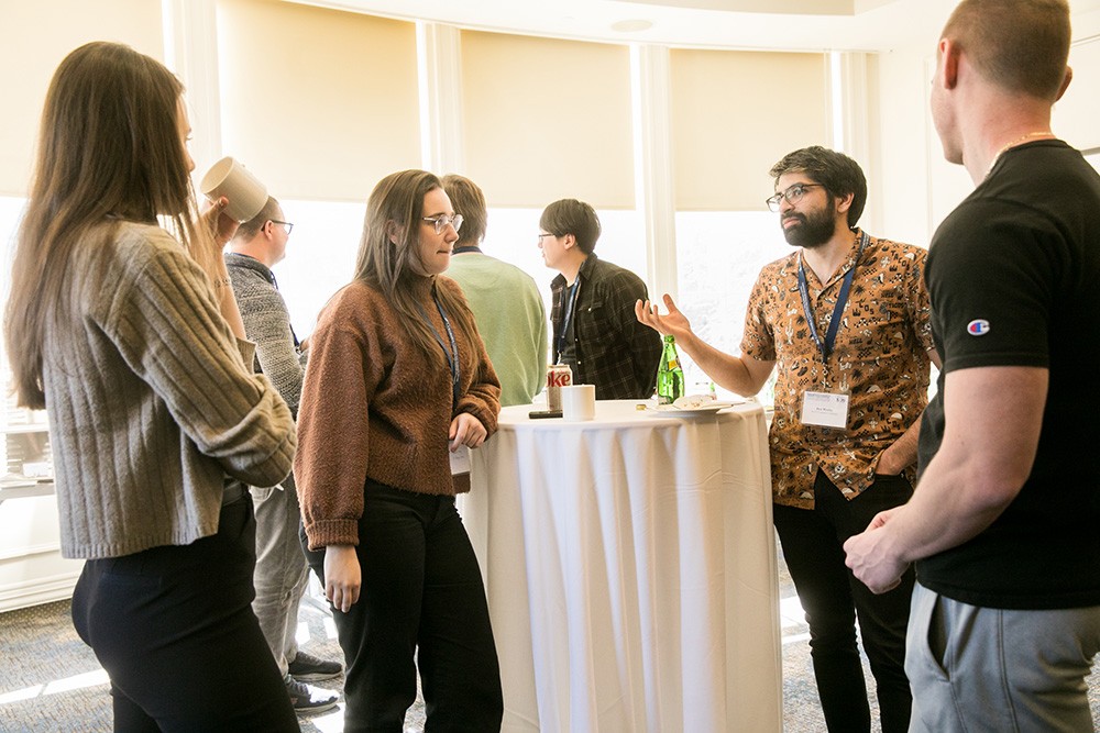 Group of people standing and chatting around a table at a conference