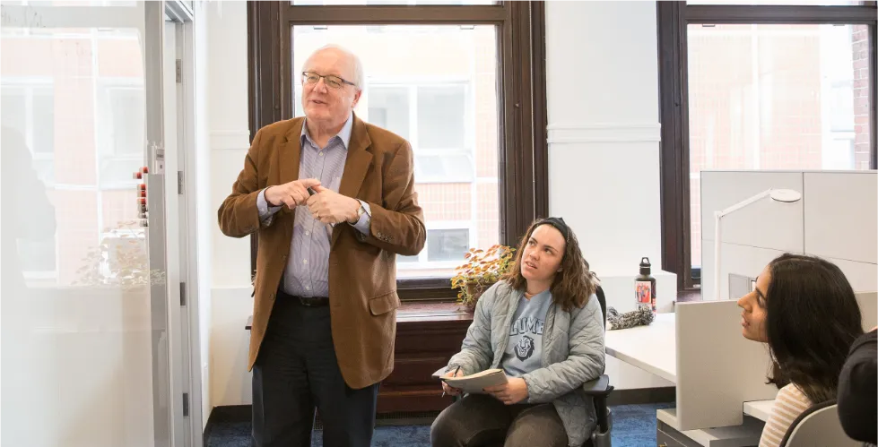 Simon Tavare with two students teaching in front of a white board 