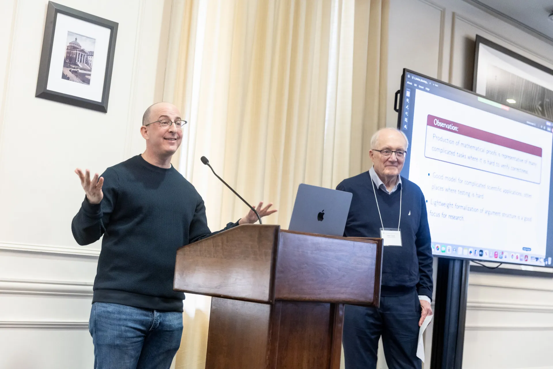 Andrew Blumberg and Simon Tavaré stand at a podium at the 2026 IICD Symposium on AI and Computation.