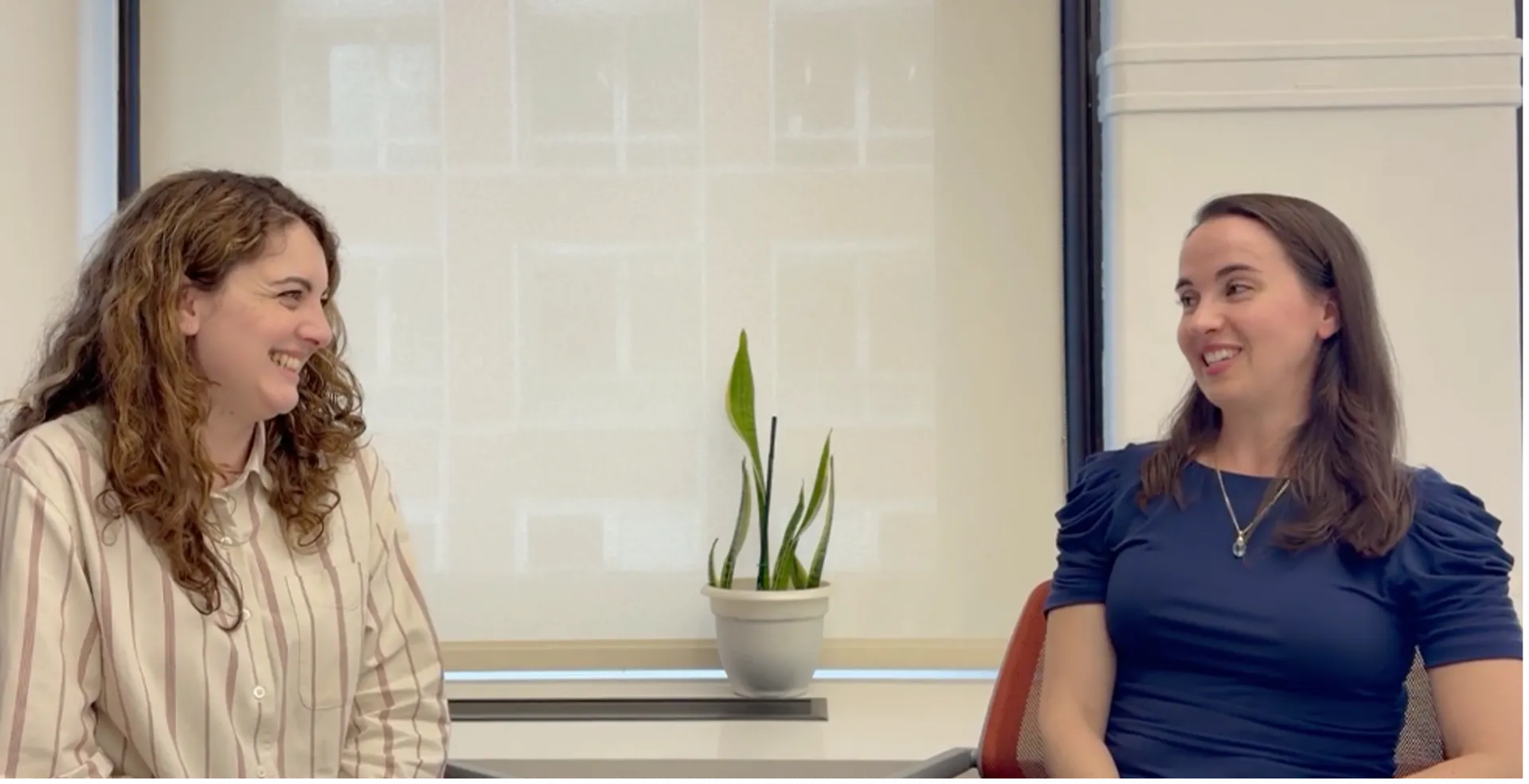 frame of Devyn Forcina, IICD Communications Specialist, sitting in a conference room with Dr. Genevera Allen during a Faces of IICD video interview.
