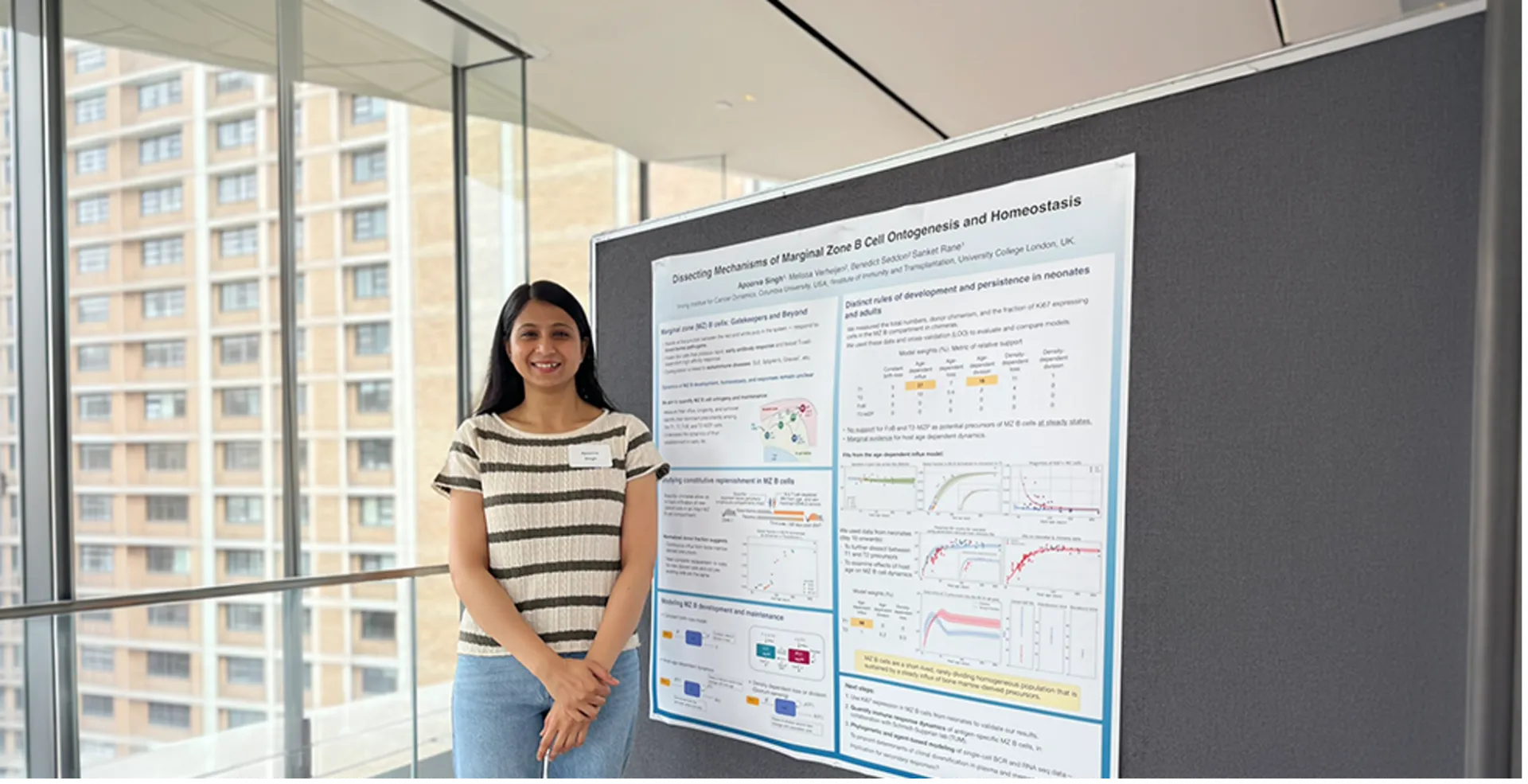 Apoorva Singh standing next to her poster at a conference