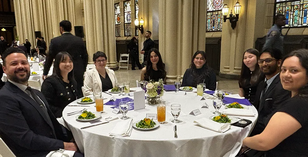 IICD staff, faculty, as well as past fellows seated around a table eating salads and holding event programs