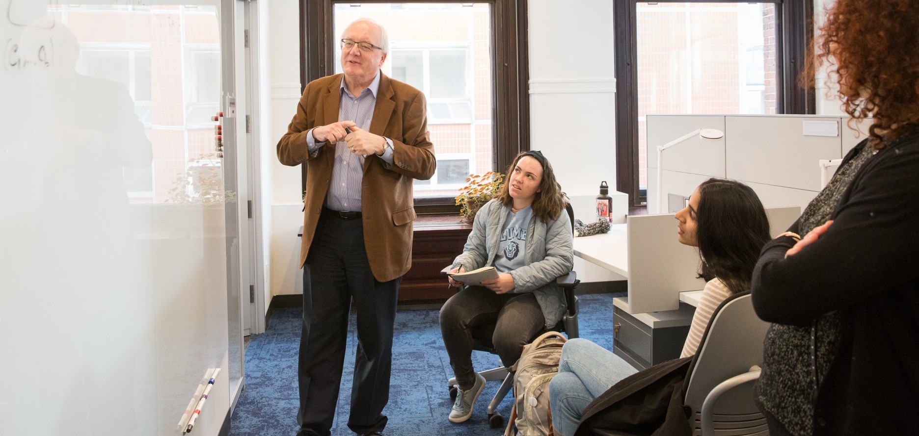 Dr. Tavaré, standing in front of a white board, teaching two students.